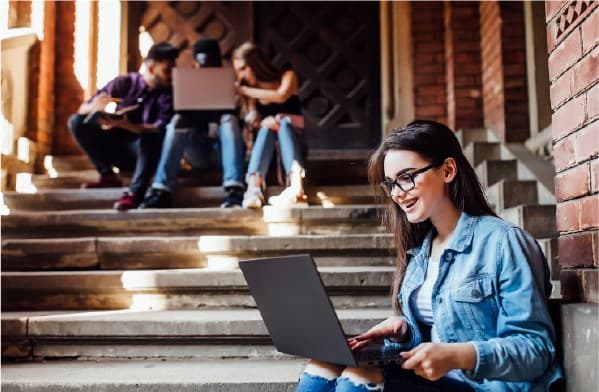 Happy women watching laptop in stairs